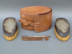 A leather cased George V hallmarked silver gentleman's travelling set comprising two brushes and