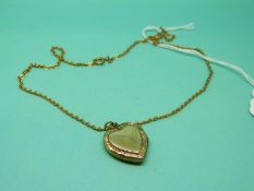 A 9ct gold locket with engraved decoration on a yellow metal chain