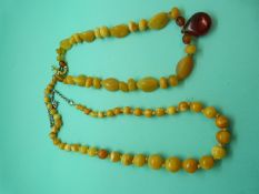 An amber necklace made up of egg yolk coloured graduated spherical beads and another amber necklace,