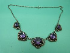 A silver Arts and Crafts necklace set with oval amethysts with floral decoration.