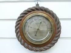 An oak aneroid barometer with curved thermometer below,