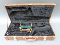 A hard saxophone case in tan leatherette finish with brassed fittings,