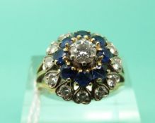 A yellow metal ring set with diamonds and sapphires in a large cluster (Size N)