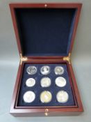 A deluxe wooden coin collector's chest containing three silver Britannia coins and six other crown