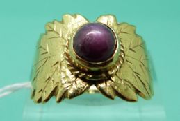 An 18ct gold ring set with a ruby cabochon showing asterism with leaf decoration (Size O)