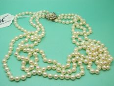 A three strand pearl necklace with a 9ct gold clasp set with 24 round brilliant cut diamonds around