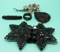 A jet buckle, two Victorian jet brooches,