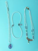 A two strand pearl necklace set with rubies and emeralds in a pendant,