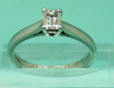 A platinum ring set with an emerald cut diamond measuring 0.