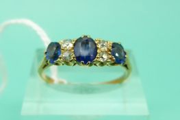 A yellow metal ring set with three sapphires and diamonds (Size P)