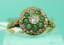 An 18ct gold Victorian ring set with a diamond surrounded by emeralds and a further row of diamonds