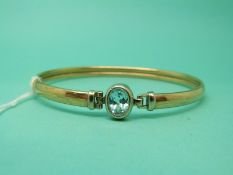 A 9ct gold bangle set with a blue topaz, 7.4g.