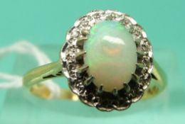 A 18ct gold ring set with an opal cabochon surrounded by diamonds in a platinum setting (Size L)