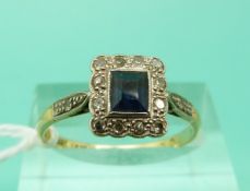 An 18ct gold ring set with a rectangular cut sapphire surrounded by diamonds in a platinum setting