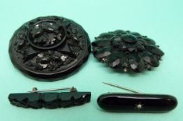 A Victorian carved jet brooch, two further jet brooches and a French faceted carved jet example.