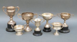 Seven various hallmarked silver twin handled trophy cups, height of largest 9.