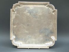 An Art Deco hallmarked silver square salver raised on four feet,