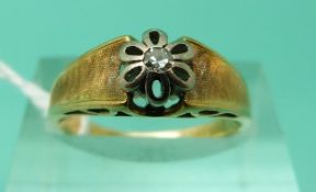 A yellow metal ring marked 585 set with a diamond in a white metal flower setting with textured