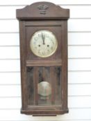 A circa 1910 oak cased two train wall clock with bevelled glass door panels and silvered Arabic