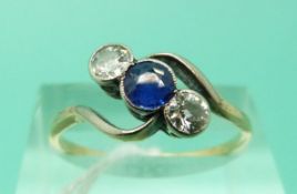 A yellow metal ring set with a sapphire and two diamonds (Size P)