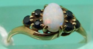 A 9ct gold ring set with an opal and sapphires (Size L)