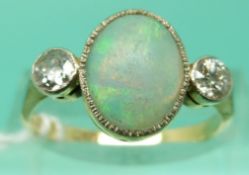 An 18ct gold ring set with an oval opal cabochon and two diamonds in a platinum setting (Size O)