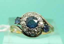 An 18ct gold ring set with three sapphires surrounded by diamonds in a platinum twist setting (Size