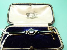 A gold bar brooch set with a round cut aquamarine and two seed pearls