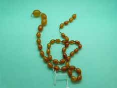 An amber necklace made up of oval translucent beads, 57g.