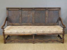 An antique oak settle with panelled and carved back,