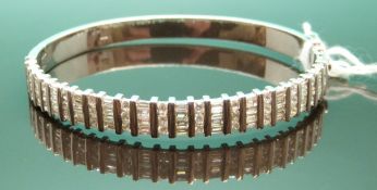 An 18ct white gold bangle set with 36 round brilliant cut diamonds and 48 baguette cut diamonds