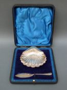 A cased George V hallmarked silver shell shaped butter dish and knife,