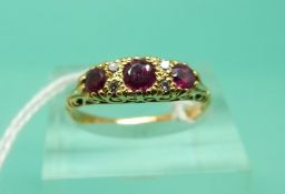 A yellow metal ring set with three rubies and diamonds (Size N)