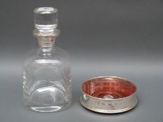 A silver wine coaster with feature hallmarks and a hallmarked silver mounted glass decanter,