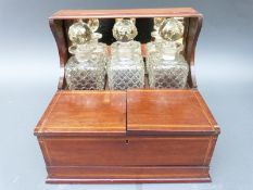 A late 19thC three bottle tantalus with inlaid decoration to the case and mirror back,