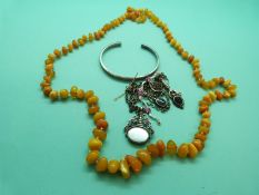 An amber necklace made of irregular butterscotch coloured beads together with a silver bangle,