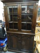 A carved oak glazed cabinet with cupboard under (H180 x W104 x D45cm)