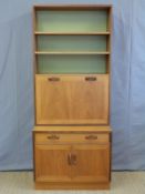 A retro G plan bookcase with fall flap bureau door opening to reveal a fitted interior above a