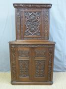 An oak Arts & Crafts corner cupboard profusely carved with flowers, foliage, lizards and 1903 date,