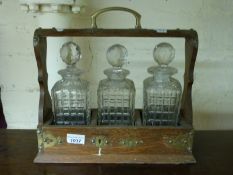 A 19thC oak three bottle tantalus,