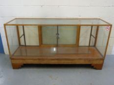 An Art Deco glazed oak haberdashery or shop fitting counter with glazed shelf and sliding doors