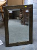 A bevelled glass mirror with hammered frame