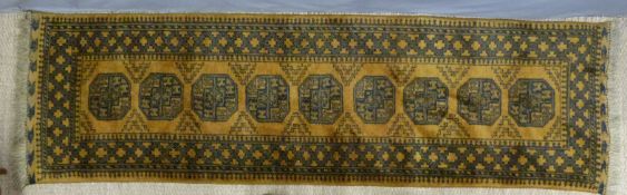 An Afghan runner with nine guls on a mustard ground (3m x 84cm)