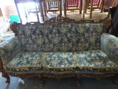 A large eight legged sofa with carved frame and two matching chairs