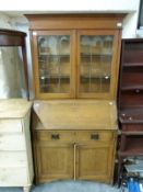 A late 19th/early 20thC oak Art Nouveau bureau bookcase, the glazed top section having two shelves,