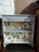 A painted side cabinet/bookcase, the bookcase lined with paper with two drawers over,