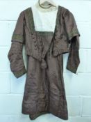 A late Victorian day outfit comprising pleated skirt and jacket finished with gold braid to the