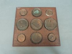 Nine bronze medallions on wooden back board to include Canterbury, St Paul's Cathedral,