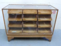 A glazed oak haberdashery or shop fitting drawer unit with twelve straight drawers with cup handles