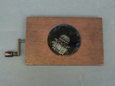 A mechanical magic lantern slide with handle depicting fish in an aquarium with coloured glass,